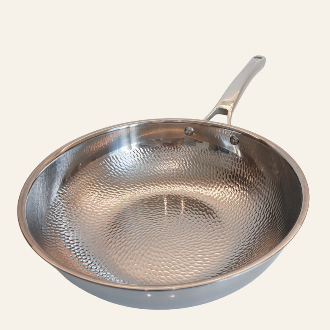 A hammered titanium frying pan with a long handle, shown from an elevated angle against a solid off-white background.